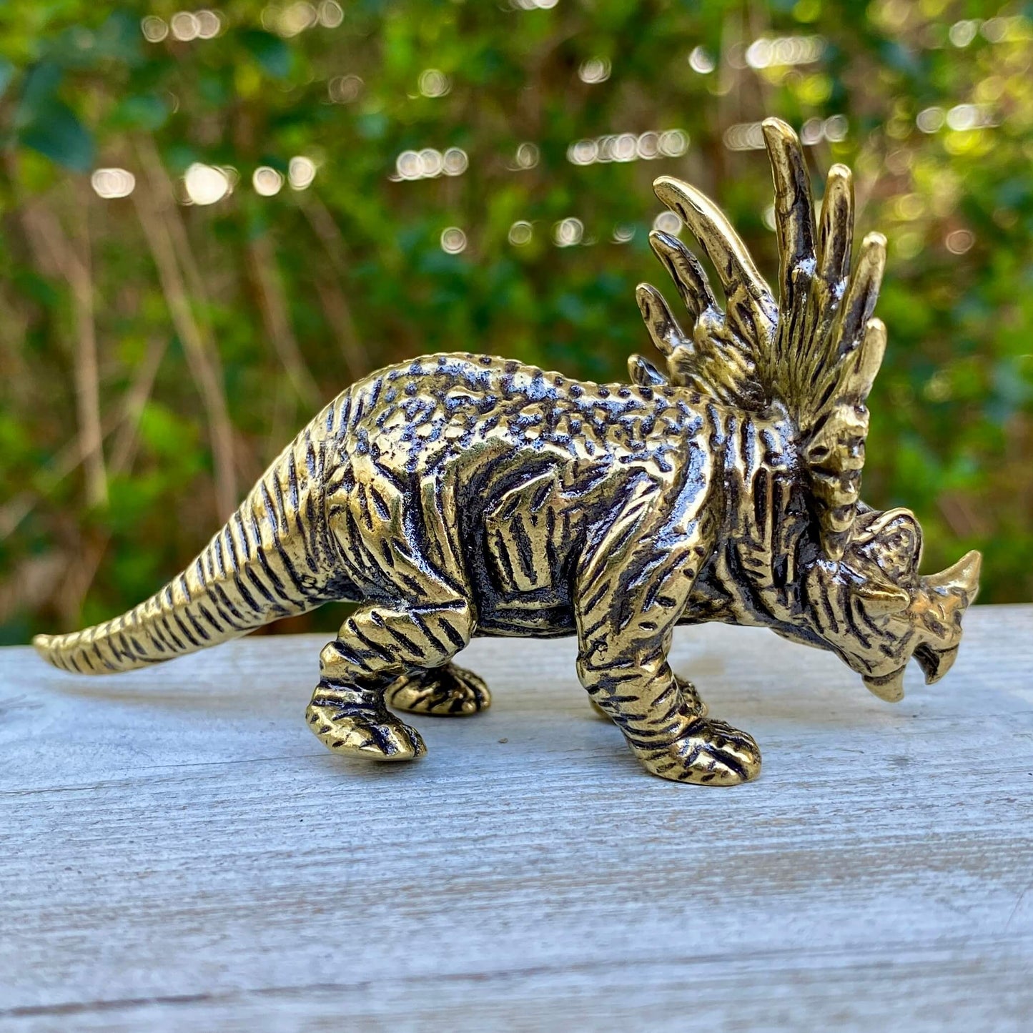 Solid brass Triceratops dinosaur figurine by Wild Brass, symbol of protection, strength, and courage, shown on a neutral background.