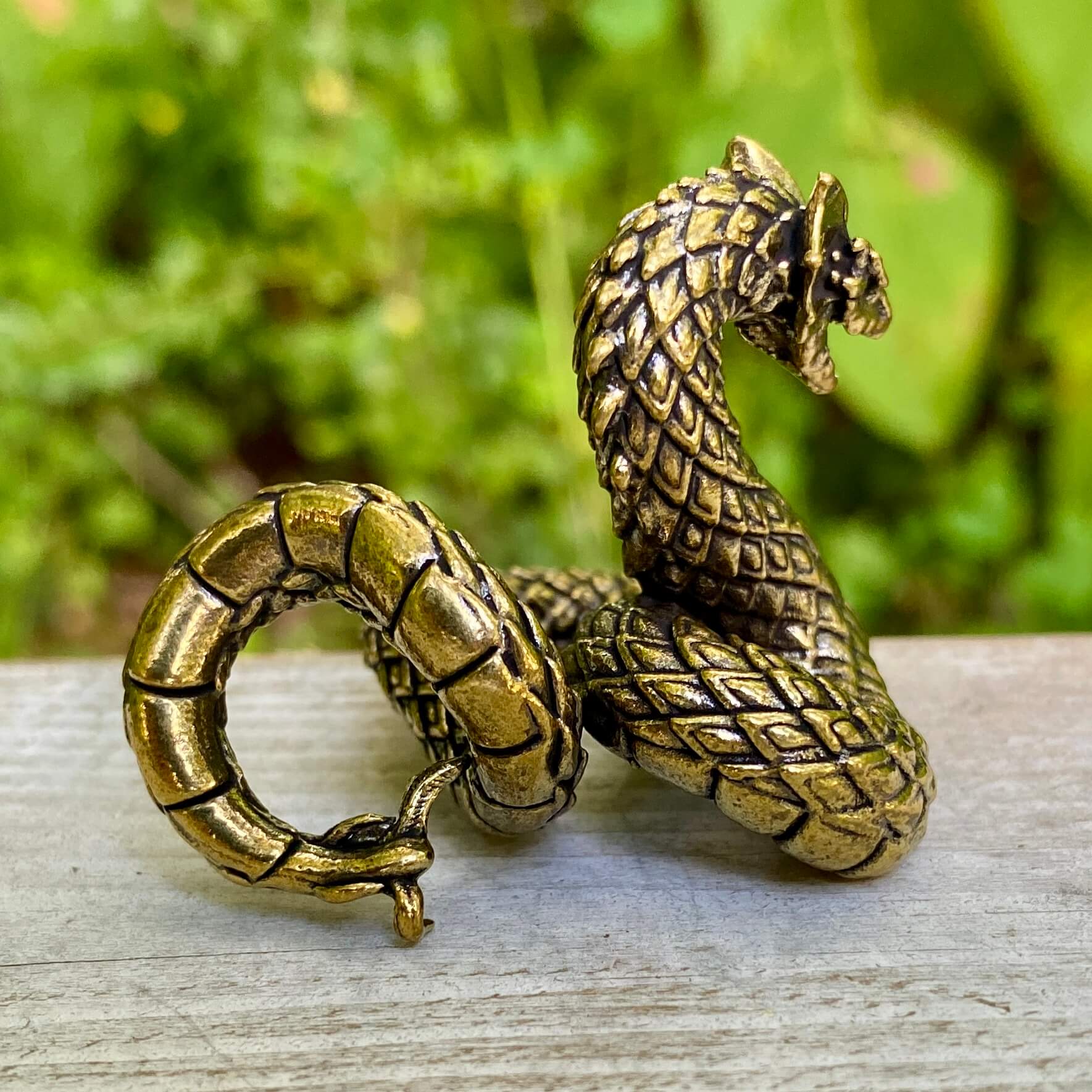 Solid brass Basilisk snake symbol from Wild Brass, representing protection, power, and transformation, shown in detailed close-up.