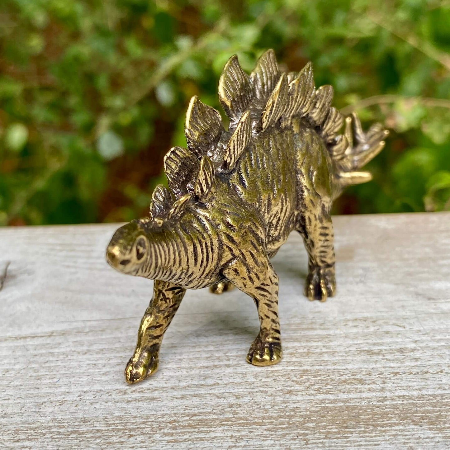 Solid brass Stegosaurus dinosaur figurine by Wild Brass, symbolizing protection, strength, and resilience, with detailed dinosaur scales.
