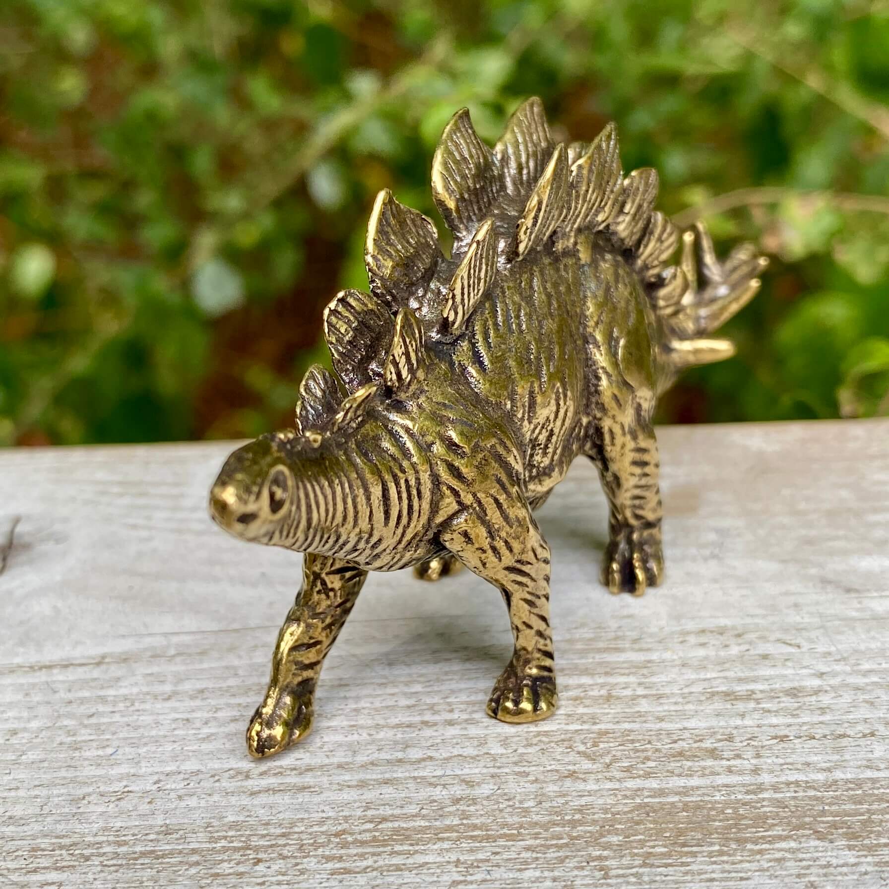 Solid brass Stegosaurus dinosaur figurine by Wild Brass, symbolizing protection, strength, and resilience, with detailed dinosaur scales.