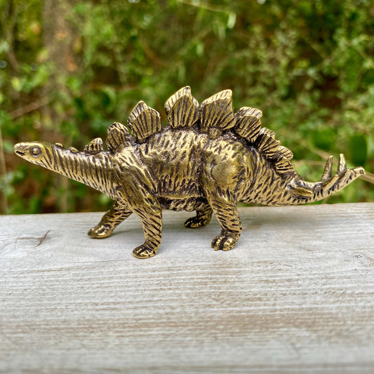 Solid brass Stegosaurus dinosaur figurine by Wild Brass, symbolizing protection, strength, and resilience, with detailed dinosaur sculpting.