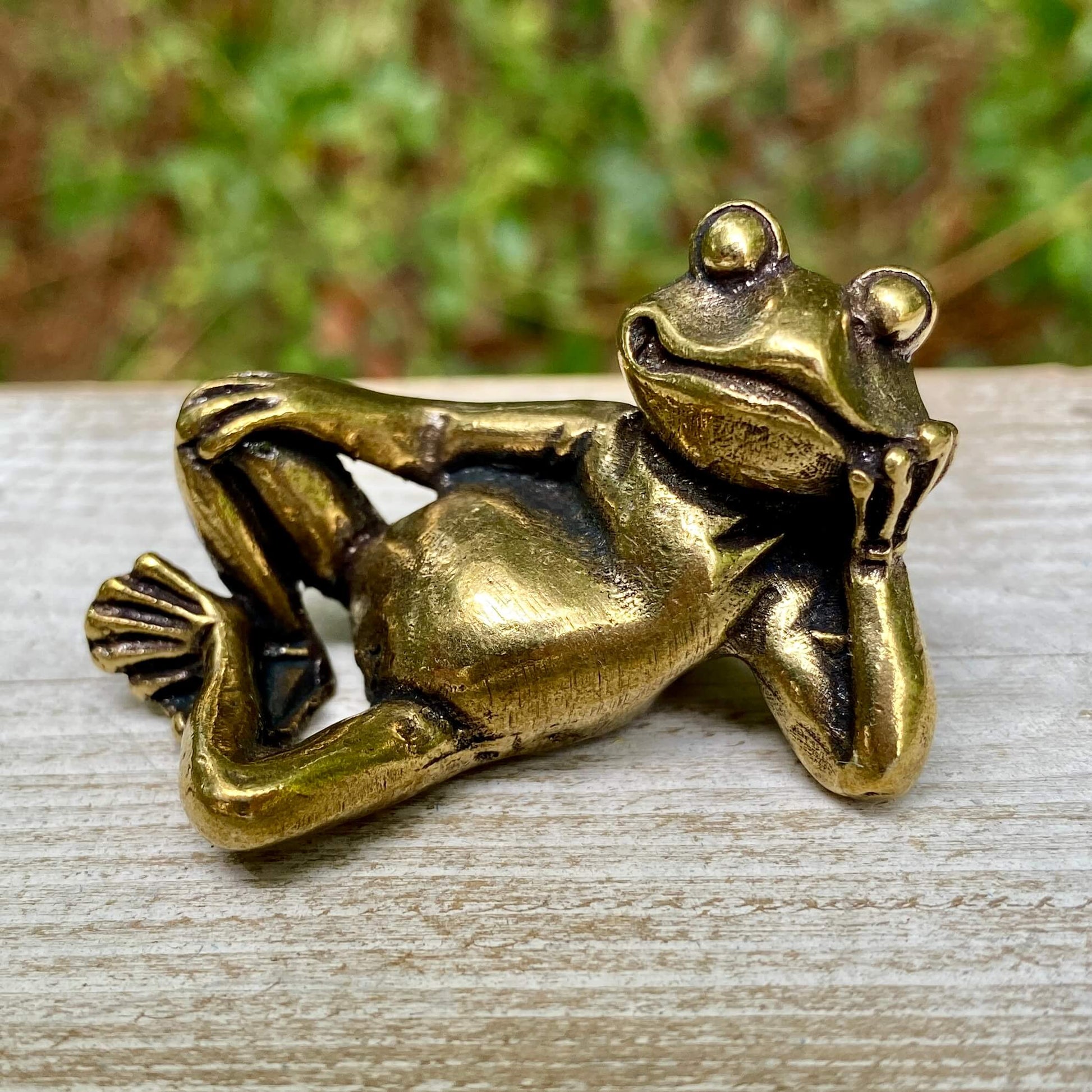 Solid brass frog lounging sculpture by Wild Brass, symbol of transformation, renewal, and luck, featuring a detailed frog figure.