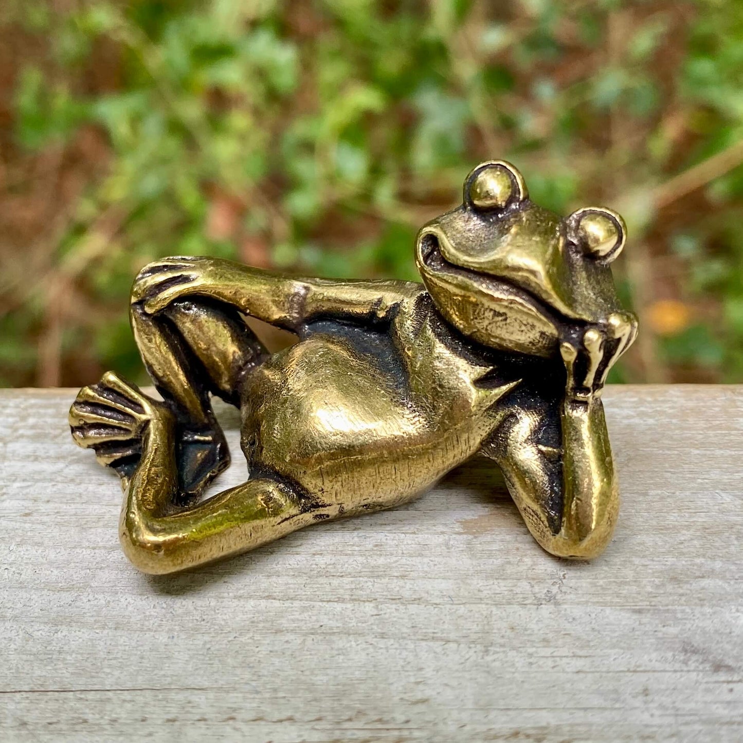 Solid brass frog lounging sculpture by Wild Brass, symbol of transformation, renewal, and luck, detailed in a natural pose.
