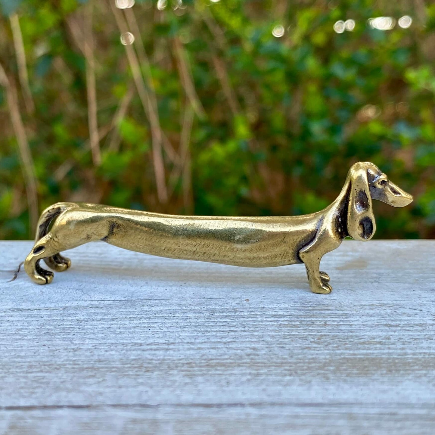 Solid brass Dachshund dog figurine by Wild Brass, symbol of courage, loyalty, and tenacity, shown in a detailed close-up image.
